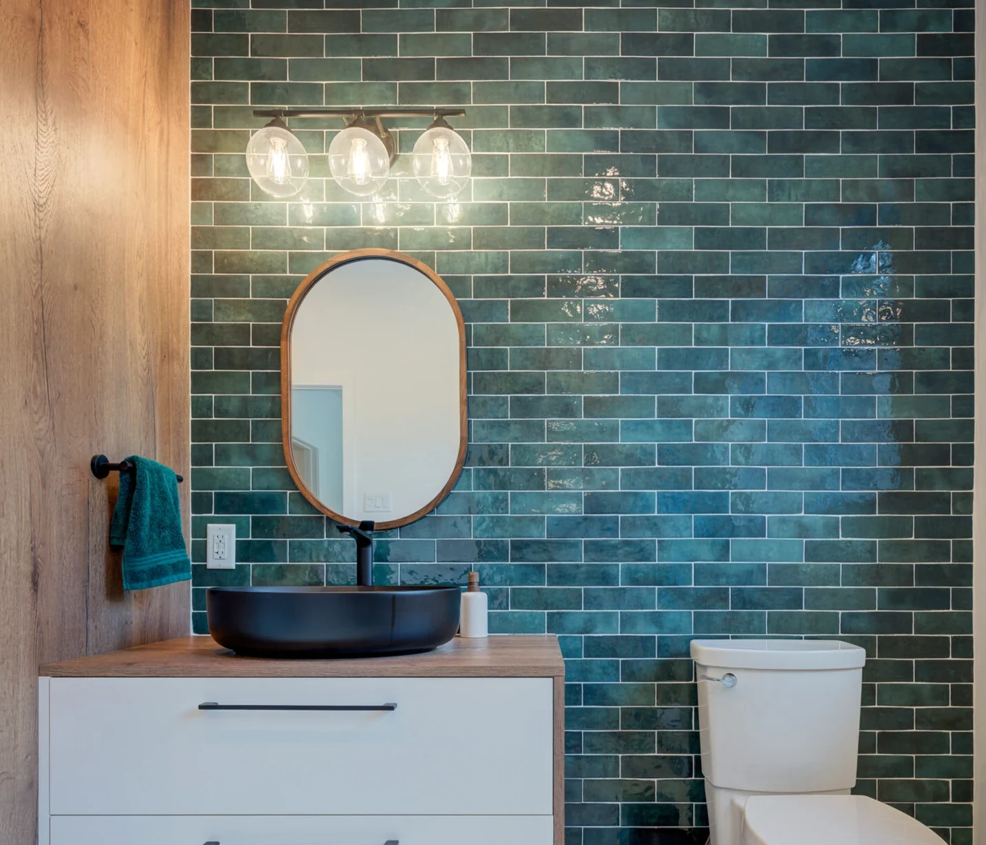 Green tiled wall and black basin