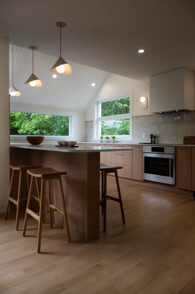 Vue de la cuisine avec îlot en bois, tabourets et suspensions