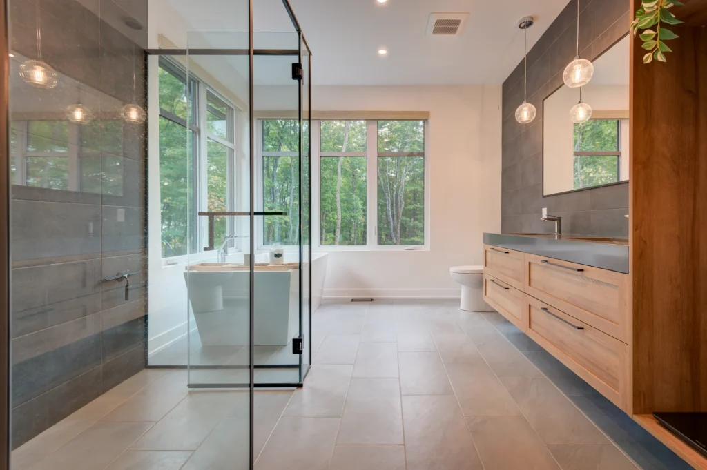 Salle de bain avec douche vitrée, vanité en bois et grande fenêtre