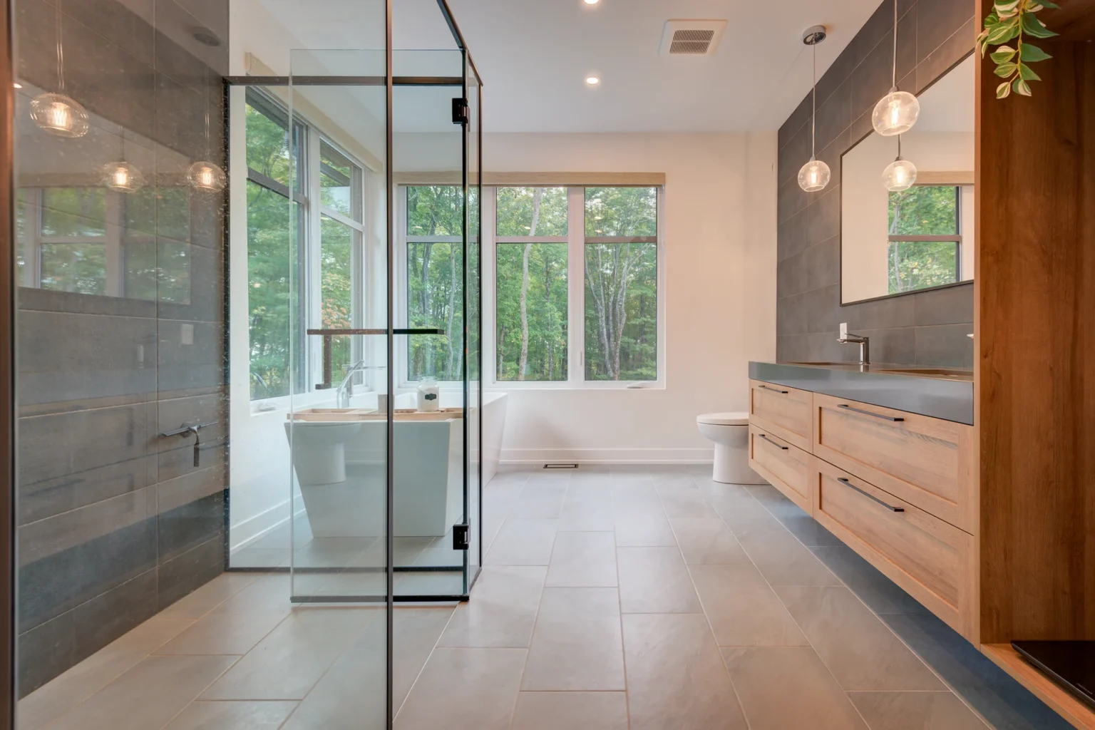 Salle de bain avec douche vitrée, baignoire et vanité en bois