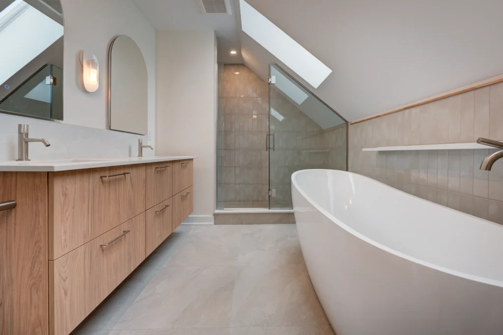 Salle de bain sous un plafond incliné avec baignoire autoportante et douche vitrée